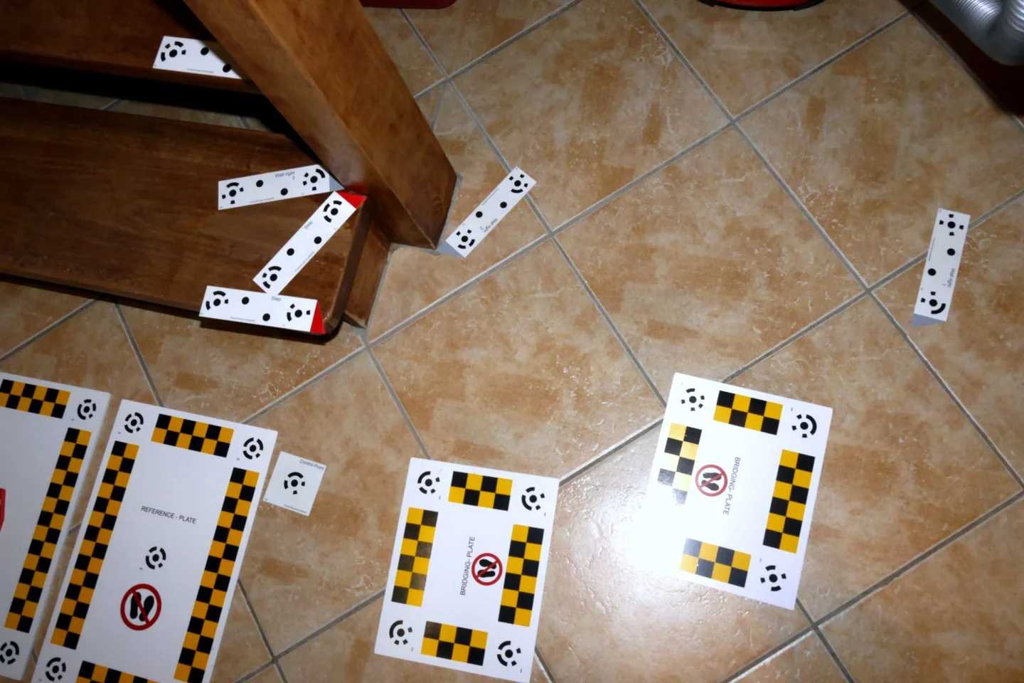 Plaques de référence et de liaison posées sur le sol carrelé au pied de l’escalier